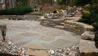 Flagstone patio surrounded by terraced limestone walls and steps on a wooded hillside